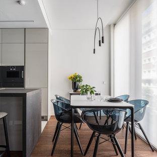 Modelo de comedor de cocina actual, sin chimenea, con paredes blancas, suelo de madera en tonos medios y suelo marrón