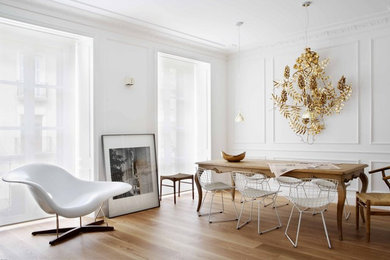На фото: столовая в скандинавском стиле с белыми стенами и светлым паркетным полом без камина