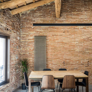 Immagine di una grande sala da pranzo industriale con pareti marroni, pavimento grigio, soffitto in legno e pareti in mattoni