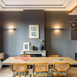 Imagen de comedor contemporáneo, abierto, con paredes grises, suelo de madera clara, chimenea tradicional y suelo beige