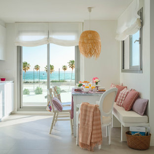 Imagen de comedor de cocina costero con paredes blancas y suelo beige