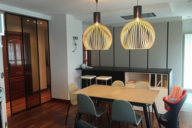 Cette image montre une salle à manger ouverte sur le salon minimaliste de taille moyenne avec un mur gris et un sol en bois brun.