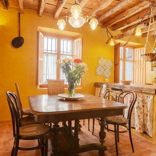 Modelo de comedor de cocina de estilo de casa de campo, sin chimenea, con paredes amarillas y suelo marrón
