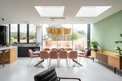 Example of a mid-sized trendy concrete floor and gray floor kitchen/dining room combo design in London with green walls