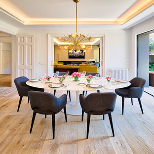 Ejemplo de comedor contemporáneo, cerrado, con paredes blancas, suelo de madera clara y suelo beige