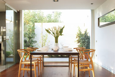 Ejemplo de comedor minimalista cerrado con paredes blancas y suelo de madera en tonos medios