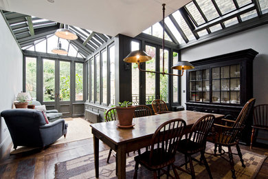 This is an example of a traditional conservatory in London with dark hardwood flooring and a glass ceiling.