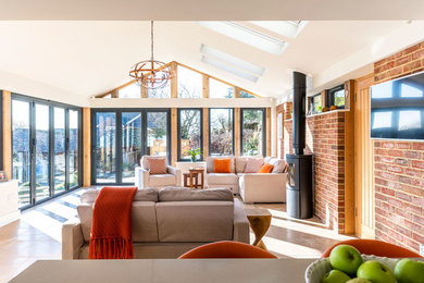 Large contemporary conservatory in Buckinghamshire with a wood burning stove, a skylight and beige floors.