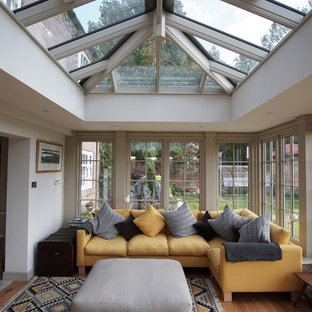 This is an example of a classic conservatory in Other with light hardwood flooring, a glass ceiling and brown floors.
