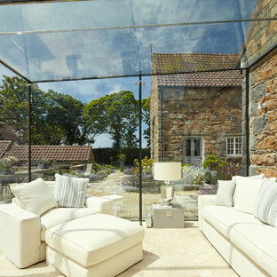 Country conservatory in Channel Islands with a glass ceiling and beige floors.