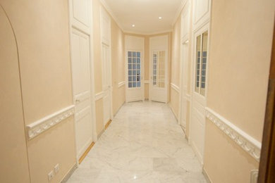 Cette image montre un grand couloir traditionnel avec un mur beige et un sol en marbre.