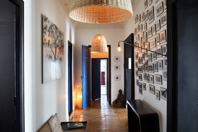 Idée de décoration pour un grand couloir design avec un mur blanc et un sol en bois brun.