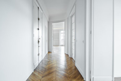 Exemple d'un grand couloir chic avec un mur blanc, un sol en bois brun et un sol marron.
