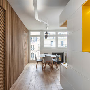 Idée de décoration pour un couloir design avec un mur jaune et un sol en bois clair.