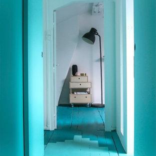 Idée de décoration pour un couloir nordique de taille moyenne avec un mur bleu et un sol en bois peint.