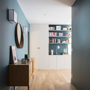 Exemple d'un couloir tendance avec un mur bleu, un sol en bois clair et un sol beige.