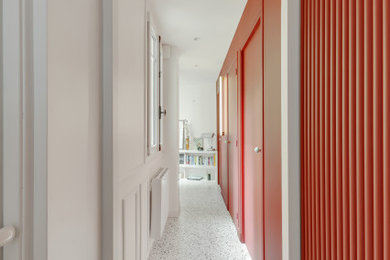 パリにあるお手頃価格のコンテンポラリースタイルのおしゃれな廊下 (赤い壁、テラゾーの床、白い床) の写真