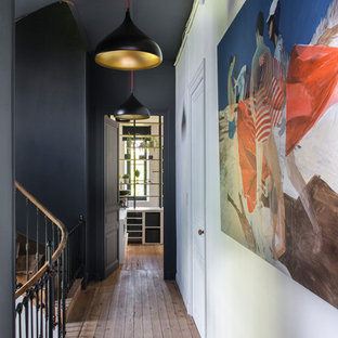 Idées déco pour un grand couloir éclectique avec un sol marron, un mur noir et un sol en bois brun.