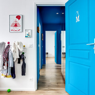 Idée de décoration pour un couloir design de taille moyenne avec un mur bleu, un sol en bois clair et un sol beige.