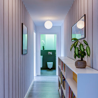 Cette image montre un couloir design de taille moyenne avec un mur blanc et un sol en bois clair.