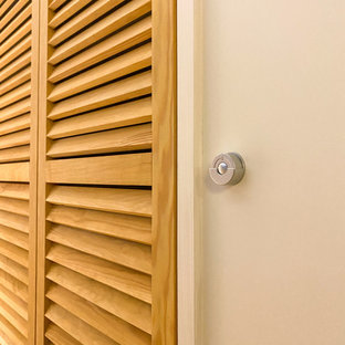 Esempio di un piccolo armadio o armadio a muro unisex design con ante a persiana, ante in legno chiaro, parquet chiaro, pavimento marrone e travi a vista