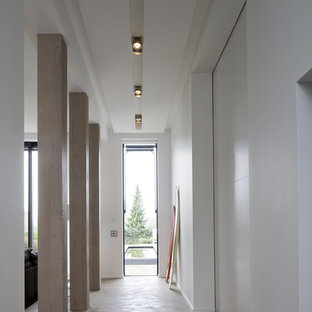Idées déco pour un grand couloir contemporain avec un mur blanc et béton au sol.