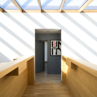Inspiration pour un couloir design de taille moyenne avec un mur blanc et un sol en bois clair.