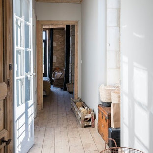 Idée de décoration pour un couloir méditerranéen avec un mur blanc, un sol en bois clair et un sol beige.