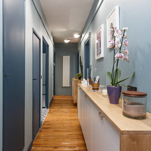 Idées déco pour un couloir contemporain avec un mur bleu, un sol en bois brun et un sol beige.