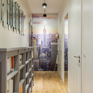 Inspiration pour un couloir design de taille moyenne avec un mur blanc et un sol en bois clair.