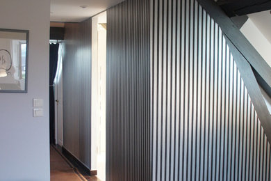 アンジェにあるトランジショナルスタイルのおしゃれな廊下 (黒い壁、濃色無垢フローリング) の写真