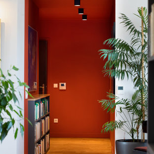Aménagement d'un couloir moderne avec un mur orange et un sol en bois clair.