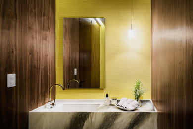 Diseño de cuarto de baño actual con paredes amarillas y encimera de mármol