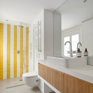 Diseño de cuarto de baño con ducha, contemporáneo, con puertas de armario de madera oscura, ducha a ras de suelo, sanitario de pared, baldosas y/o azulejos amarillos, baldosas y/o azulejos blancos, paredes blancas, suelo de cemento, lavabo sobreencimera, suelo gris, encimeras blancas y armarios con paneles lisos