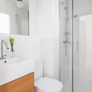 Foto de cuarto de baño con ducha, escandinavo, con armarios con paneles lisos, puertas de armario de madera oscura, sanitario de dos piezas, baldosas y/o azulejos blancos, baldosas y/o azulejos de cemento, paredes blancas y suelo multicolor