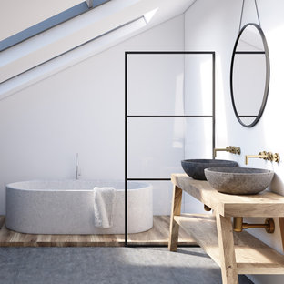 Modelo de cuarto de baño con ducha, nórdico, con armarios abiertos, bañera exenta, paredes blancas, suelo de cemento, lavabo sobreencimera, encimera de madera, suelo gris y encimeras beige