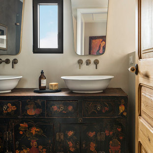 Diseño de cuarto de baño mediterráneo, de tamaño medio, con armarios tipo mueble, puertas de armario con efecto envejecido, baldosas y/o azulejos multicolor, baldosas y/o azulejos de cerámica, paredes beige, suelo de baldosas de cerámica, lavabo sobreencimera, encimera de madera, suelo multicolor y encimeras negras