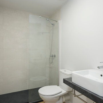Baño moderno con encimera de mármol, mampara de cristal fija y radiador de baño