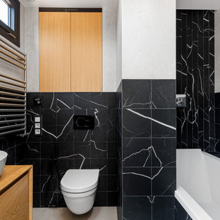 Imagen de cuarto de baño principal, único y de pie, contemporáneo, de tamaño medio, con armarios con paneles empotrados, puertas de armario blancas, bañera empotrada, sanitario de pared, baldosas y/o azulejos blancas y negros, paredes negras, lavabo sobreencimera, encimera de madera y suelo beige