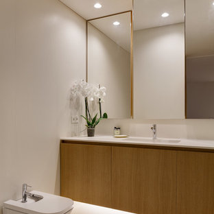 Foto de cuarto de baño principal, minimalista, con armarios con paneles lisos, puertas de armario de madera oscura, ducha a ras de suelo, sanitario de pared, suelo de cemento, encimera de cuarzo compacto, suelo blanco, ducha abierta, encimeras blancas, paredes beige y lavabo bajoencimera