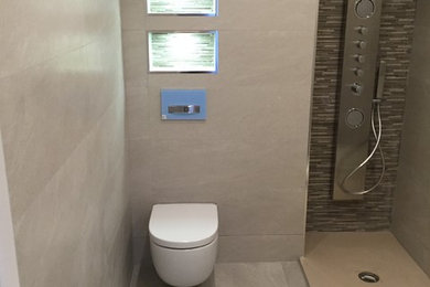 Modelo de cuarto de baño contemporáneo de tamaño medio con ducha abierta, sanitario de pared, paredes blancas, aseo y ducha y lavabo integrado