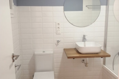 Ejemplo de cuarto de baño flotante de tamaño medio con bañera empotrada, baldosas y/o azulejos blancos, suelo laminado, lavabo sobreencimera, encimera de madera y cuarto de baño