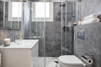 Ejemplo de cuarto de baño contemporáneo de tamaño medio con armarios con paneles lisos, puertas de armario blancas, sanitario de una pieza, paredes grises, aseo y ducha y lavabo integrado