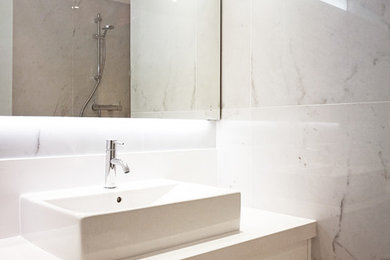 バルセロナにあるトランジショナルスタイルのおしゃれな浴室 (バリアフリー、分離型トイレ、白いタイル、大理石タイル、白い壁、大理石の床、ベッセル式洗面器、白い床、白い洗面カウンター) の写真
