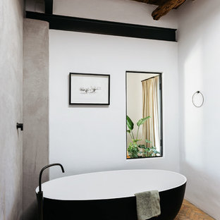 Mediterranean bathroom in Other with a freestanding tub, white walls, brick floors and brown floor.