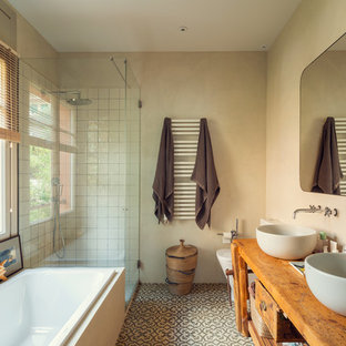Foto de cuarto de baño principal, mediterráneo, con lavabo sobreencimera, ducha con puerta con bisagras, armarios tipo mueble, puertas de armario de madera oscura, bañera encastrada, ducha esquinera, sanitario de una pieza, baldosas y/o azulejos blancos, baldosas y/o azulejos de cerámica, paredes beige, encimera de madera, suelo multicolor y encimeras marrones
