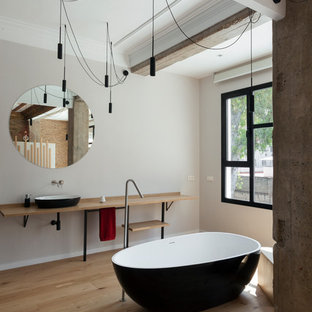 Foto de cuarto de baño principal, contemporáneo, grande, con suelo de madera en tonos medios, bañera exenta, paredes grises, lavabo sobreencimera, encimera de madera, suelo beige y encimeras beige