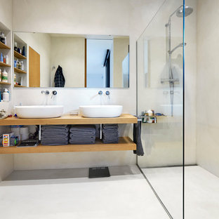 Imagen de cuarto de baño con ducha y microcemento, contemporáneo, con armarios abiertos, puertas de armario de madera oscura, ducha a ras de suelo, lavabo sobreencimera, encimera de madera, paredes beige, suelo de cemento, suelo beige, ducha abierta y encimeras marrones