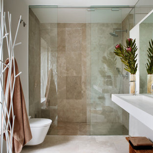 Imagen de cuarto de baño con ducha, actual, de tamaño medio, con ducha empotrada, sanitario de pared, baldosas y/o azulejos de piedra, paredes blancas, suelo de travertino, lavabo de seno grande y encimera de acrílico