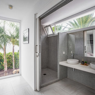 Diseño de cuarto de baño contemporáneo con ducha esquinera, baldosas y/o azulejos grises, baldosas y/o azulejos en mosaico, paredes blancas, lavabo sobreencimera, suelo gris, ducha abierta y encimeras blancas